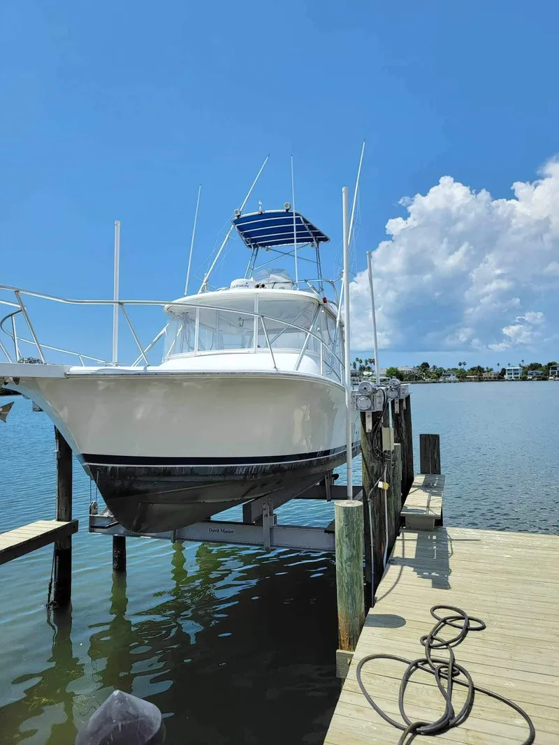 Slide: The Image of 1997 Luhrs 32 Open boat docked on a lift under a clear blue sky. - 11