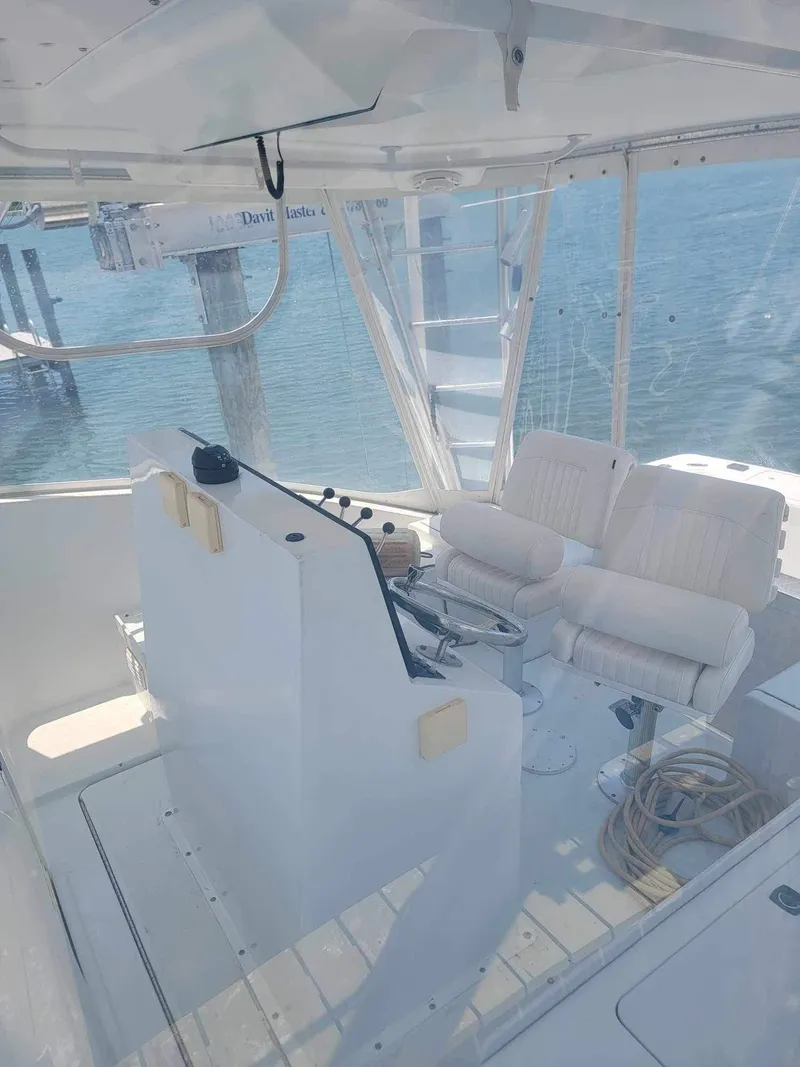 Slide: The Image of 1997 Luhrs 32 Open boat interior with helm and seating, docked by the water. - 17