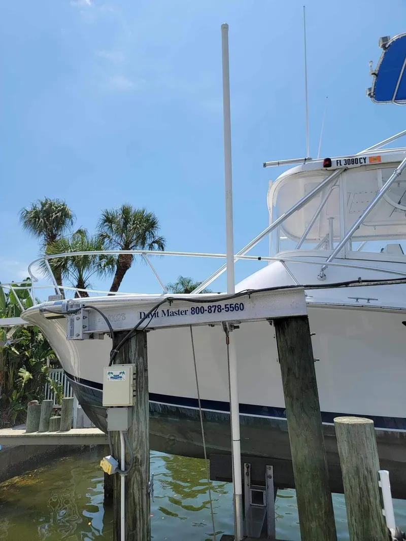 Slide: The Image of 1997 Luhrs 32 Open boat docked, surrounded by palm trees under a clear blue sky. - 4