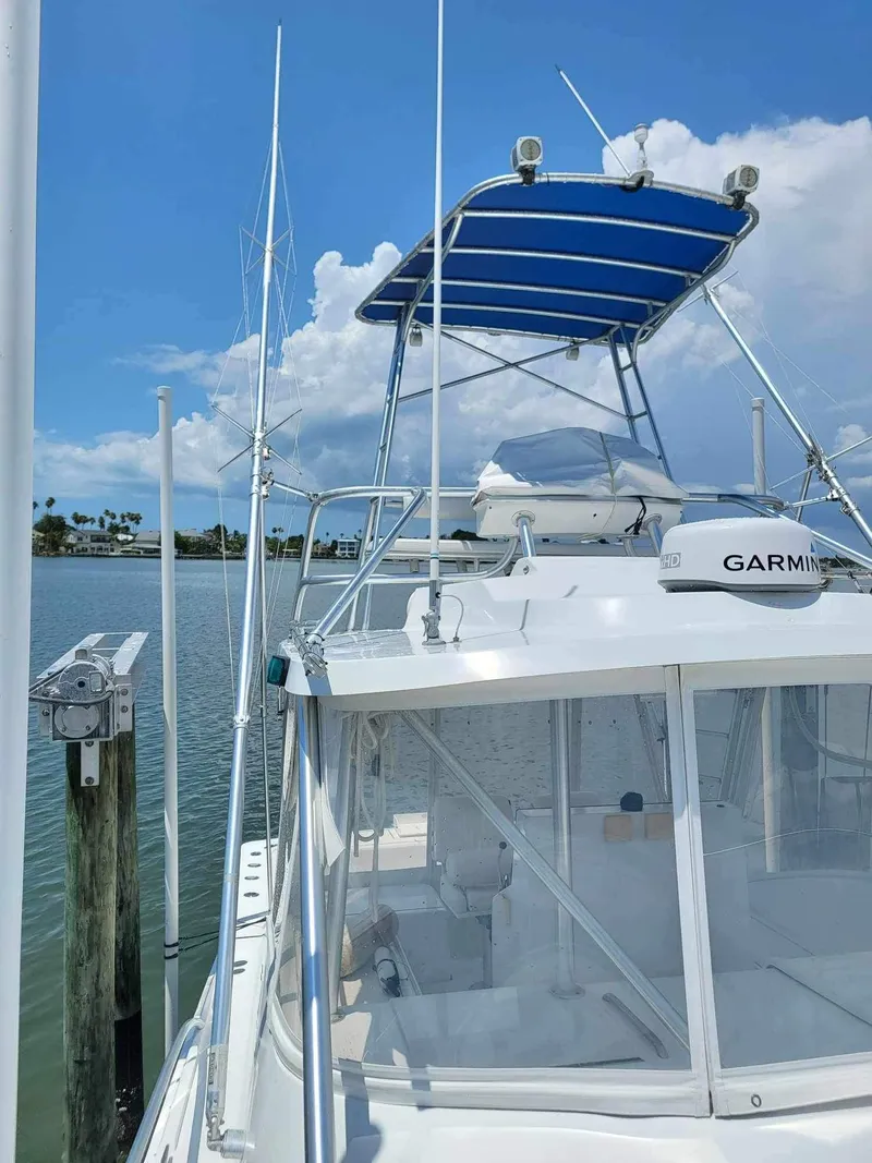 Slide: The Image of 1997 Luhrs 32 Open boat docked, featuring a blue canopy and Garmin equipment. - 42