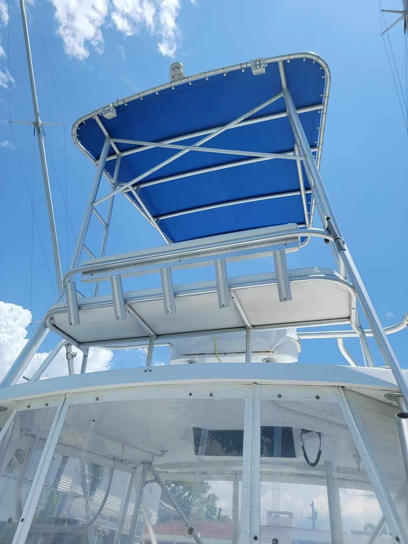 Slide: The Image of 1997 Luhrs 32 Open boat with blue canopy and clear windows under a sunny sky. - 43
