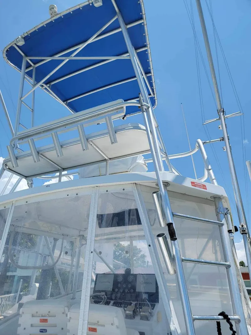 Slide: The Image of 1997 Luhrs 32 Open boat with blue canopy and ladder, clear sky background. - 44