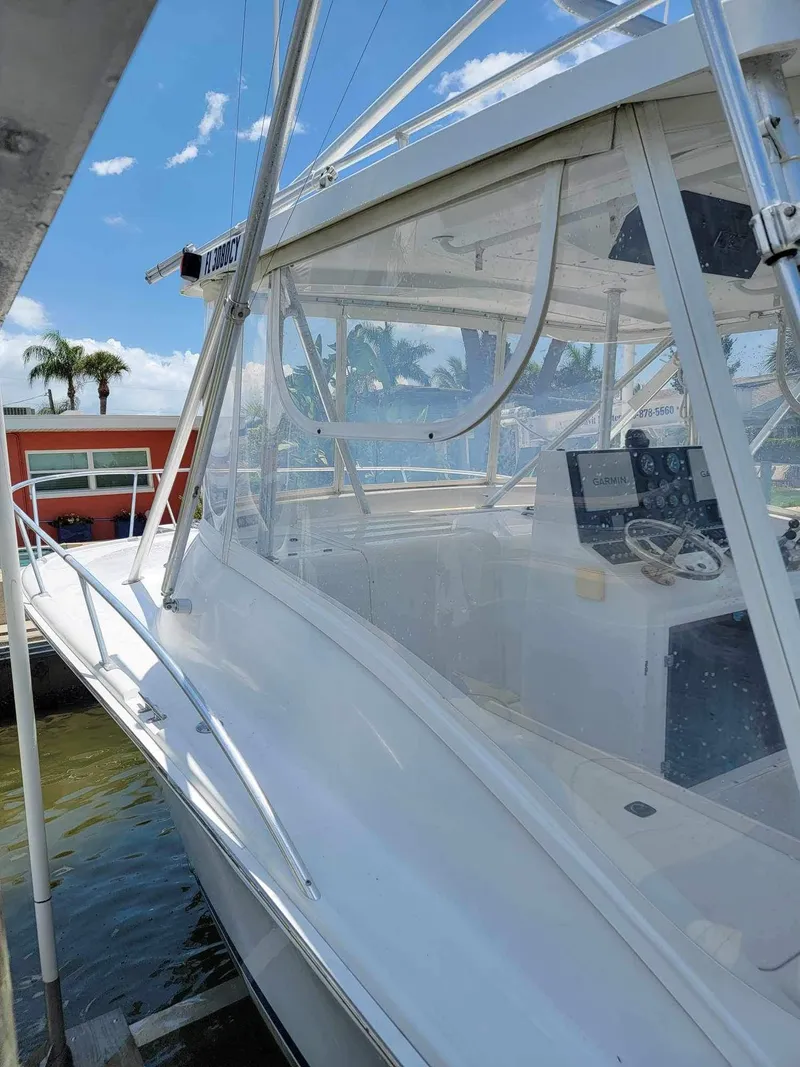 Slide: The Image of 1997 Luhrs 32 Open boat with clear enclosure, docked under a sunny sky. - 46