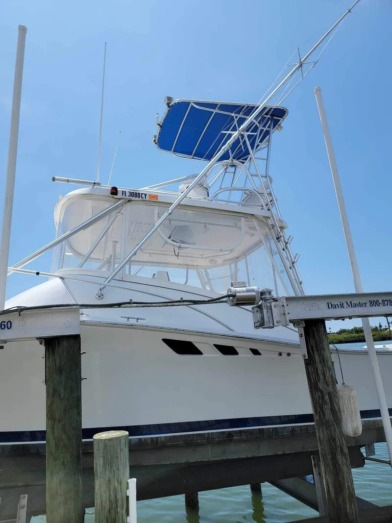 Slide: The Image of 1997 Luhrs 32 Open boat docked, featuring a blue canopy and fishing tower. - 5