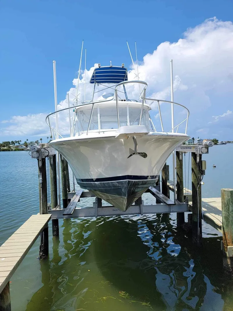 Slide: The Image of 1997 Luhrs 32 Open boat on lift, docked by calm waters under a clear sky. - 9