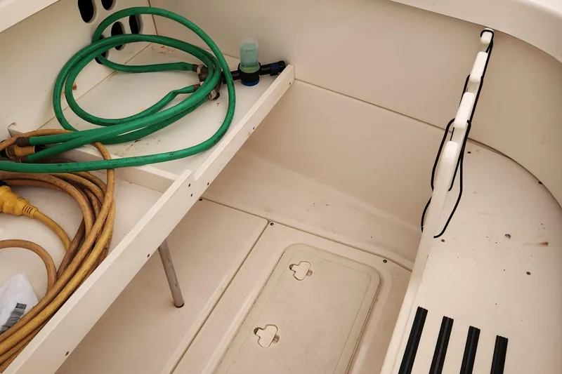 Slide: The Image of 2014 Boston Whaler 350 Outrage boat deck with storage compartments and hoses. - 26