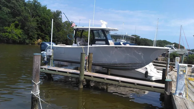 Slide: The Image of 2022 Sportsman Open 302 Center Console boat docked at a marina. - 1