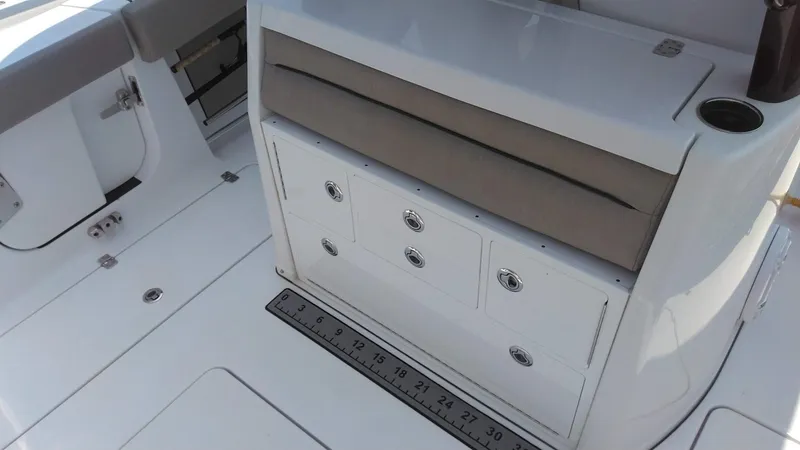 Slide: The Image of 2022 Sportsman Open 302 Center Console boat interior with storage drawers and measuring ruler. - 4