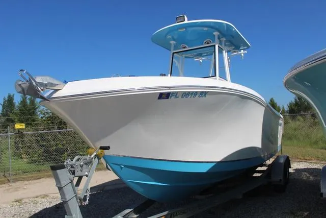 Slide: The Image of 2021 Release 240 RX boat on trailer, white and blue hull, parked outdoors. - 3