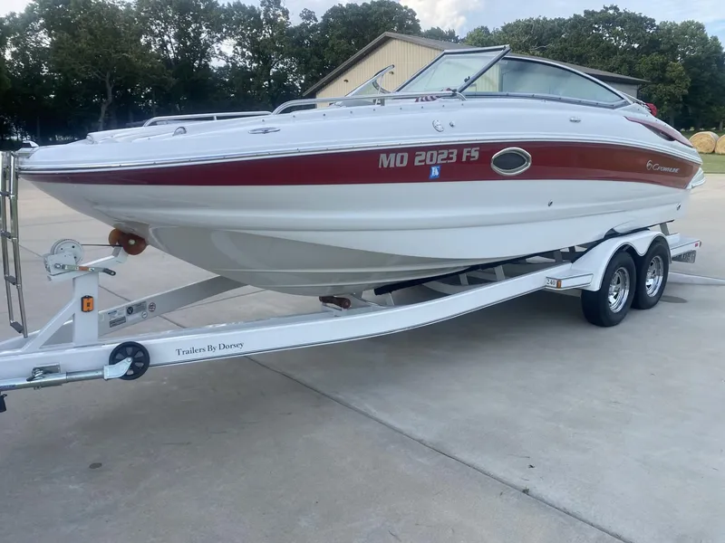 Slide: The Image of 2011 Crownline 240EX boat on trailer, white with red accents, parked outdoors. - 1