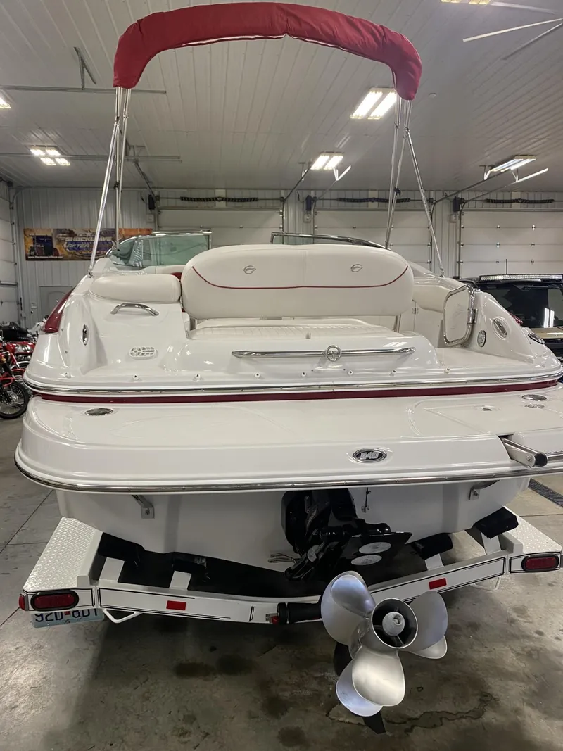 Slide: The Image of 2011 Crownline 240EX boat with red canopy in a garage setting. - 11