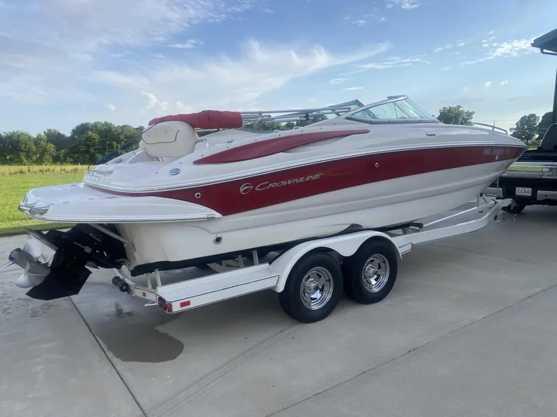 Slide: The Image of 2011 Crownline 240EX boat on trailer, red and white design, parked outdoors. - 4