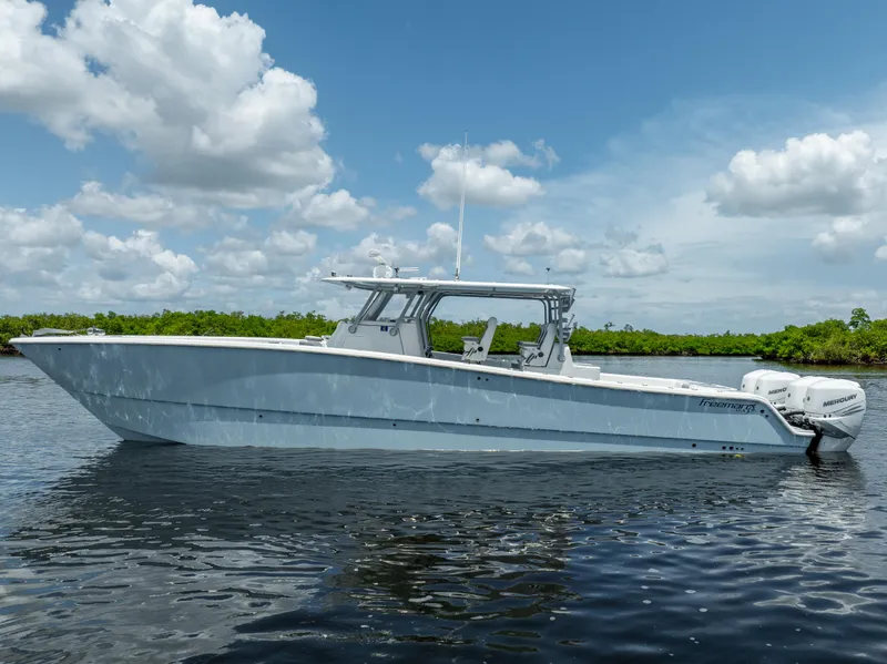 Slide: The Image of 2019 Freeman 42 LR boat on calm water with blue sky and clouds. - 0