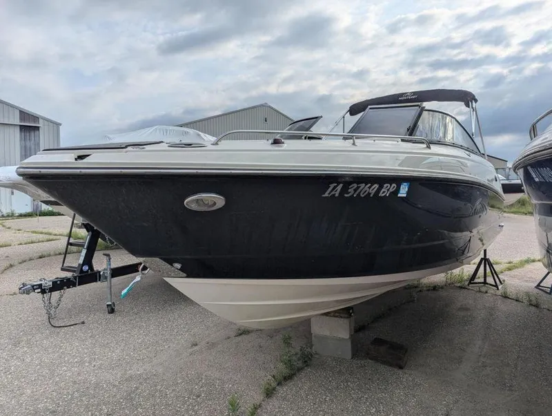 Slide: The Image of 2011 Monterey 264 FS boat on trailer, black hull, docked outdoors. - 2