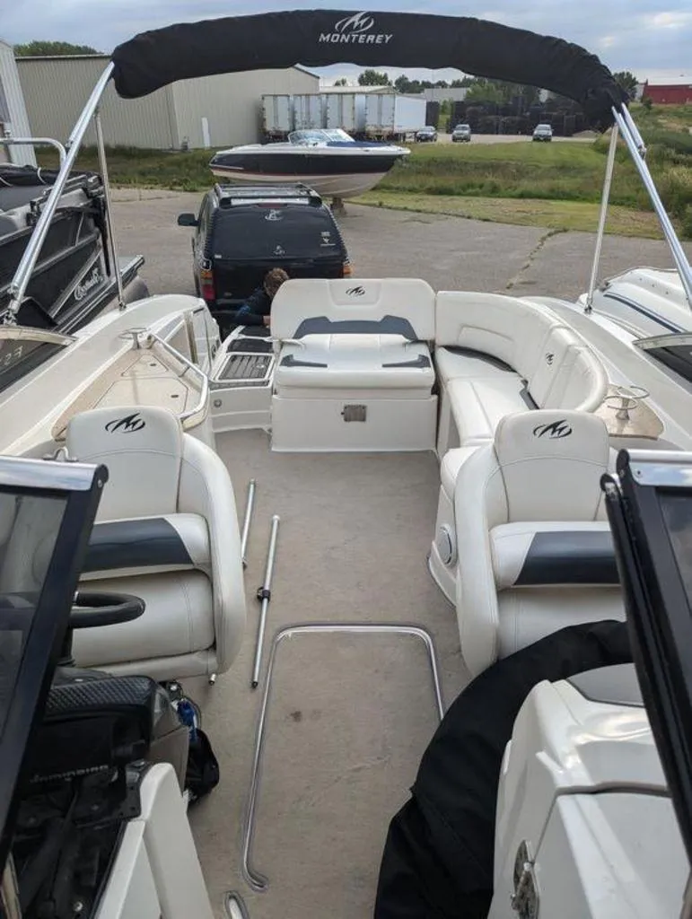 Slide: The Image of 2011 Monterey 264 FS boat interior with white seating and black canopy. - 7