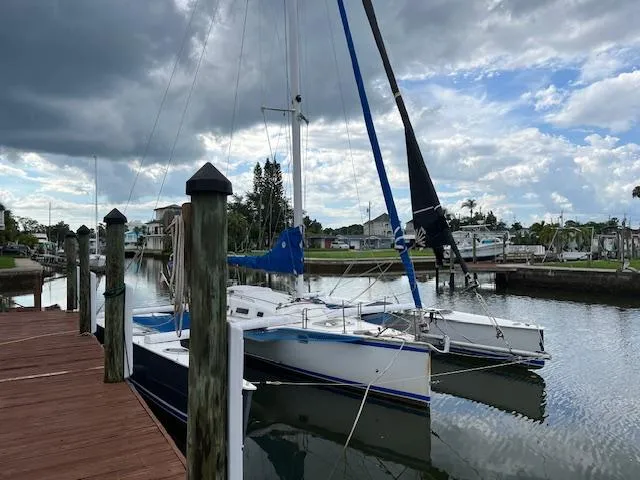The Image of 1999 Contour 34 SC sailboat docked at a marina under a cloudy sky. - 0