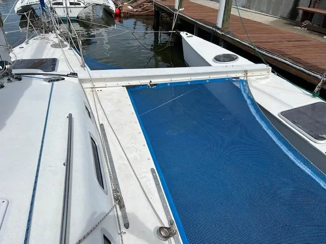 Slide: The Image of 1999 Contour 34 SC sailboat docked, featuring a blue net trampoline and white deck. - 10