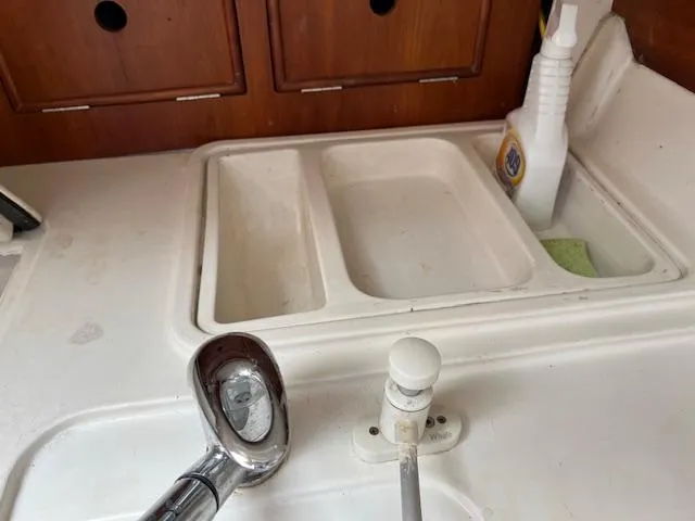 Slide: The Image of 1999 Contour 34 SC boat kitchen sink with faucet and cleaning supplies. - 25