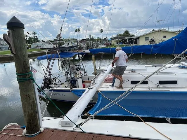 Slide: The Image of Man working on a 1999 Contour 34 SC sailboat docked at a marina. - 3