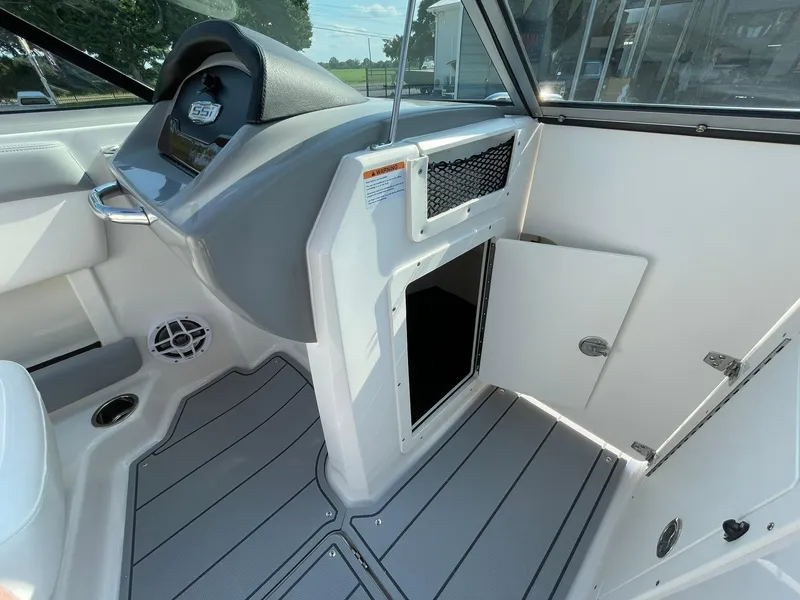 Slide: The Image of 2024 Chaparral 21 SSi OB boat interior, featuring helm and storage compartment. - 18