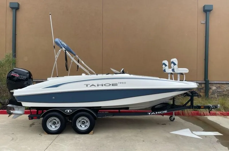 Slide: The Image of 2024 Tahoe 1950 boat on trailer, white and blue design, parked outdoors. - 2