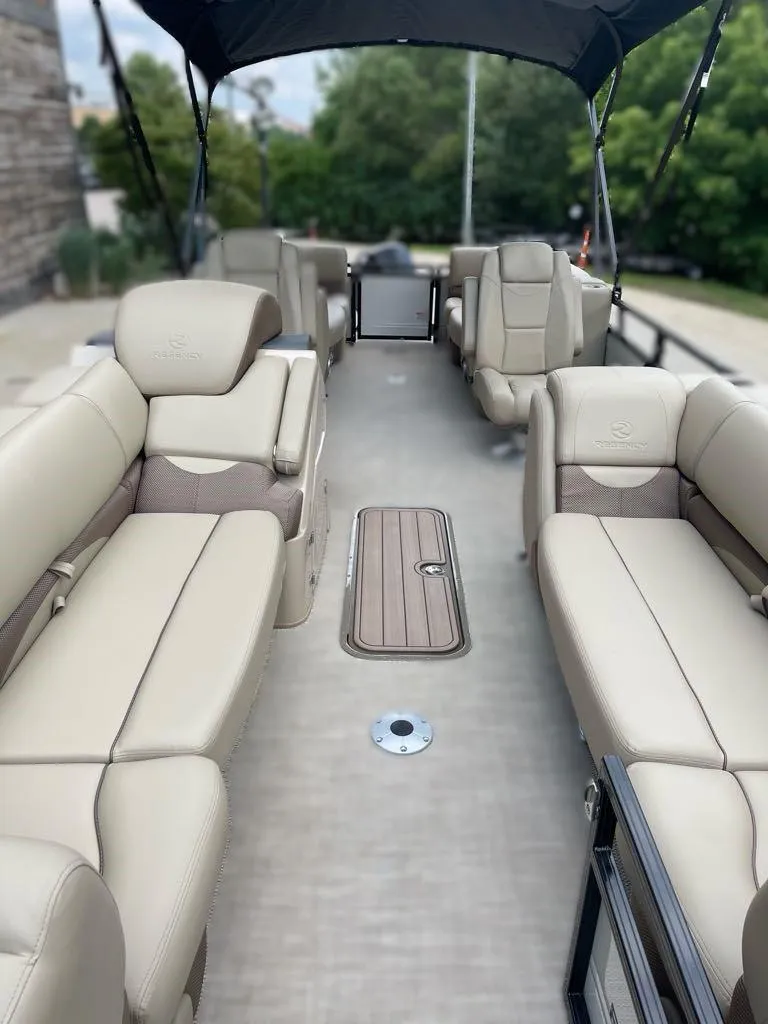 Slide: The Image of 2024 Regency 230 DL3 pontoon boat interior with beige seating and canopy. - 3