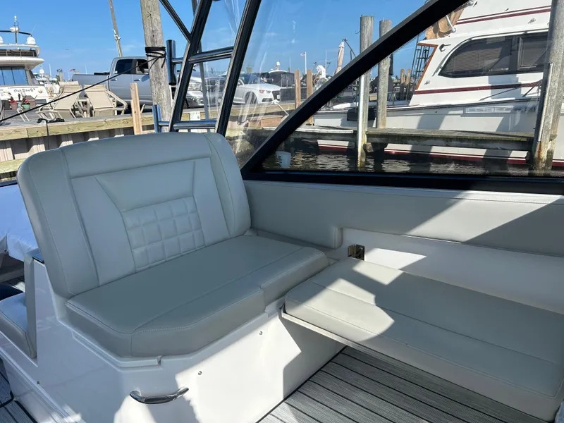 Slide: The Image of 2019 Everglades 340DC boat interior with white seating and marina view. - 12