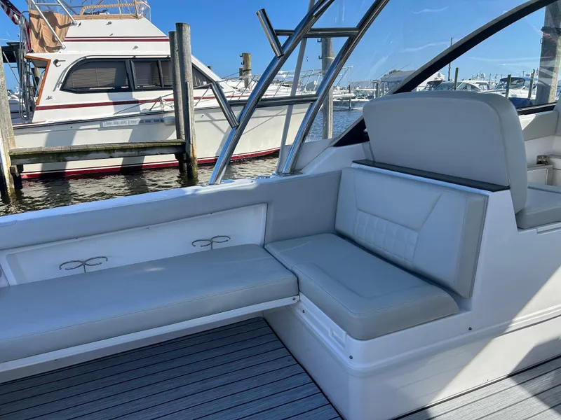 Slide: The Image of 2019 Everglades 340DC boat interior with white seating and docked boats in the background. - 22