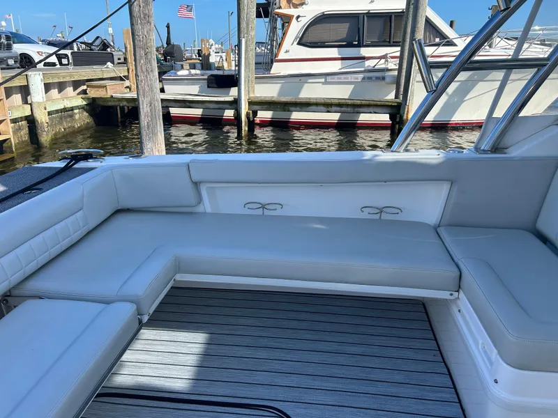Slide: The Image of 2019 Everglades 340DC boat interior with white cushioned seating at a marina. - 23