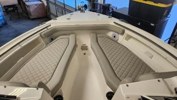 Slide: The Image of 2024 Pursuit DC 246 Dual Console boat interior with cushioned seating in a showroom. - 13