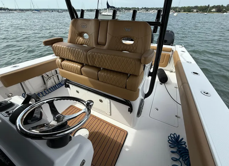 Slide: The Image of 2020 Southport 33 FE boat interior with tan seating and steering wheel, docked on water. - 7