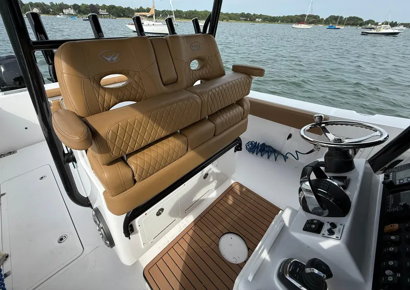 Slide: The Image of 2020 Southport 33 FE boat interior with tan leather seating and steering wheel, docked on calm water. - 9