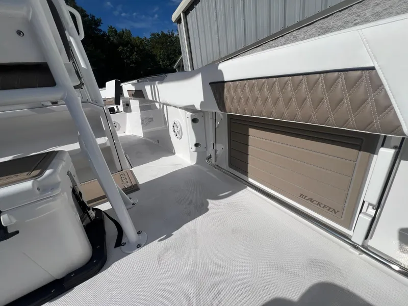 Slide: The Image of 2025 Blackfin 222 CC boat interior with white and tan upholstery, storage compartments, and seating. - 16
