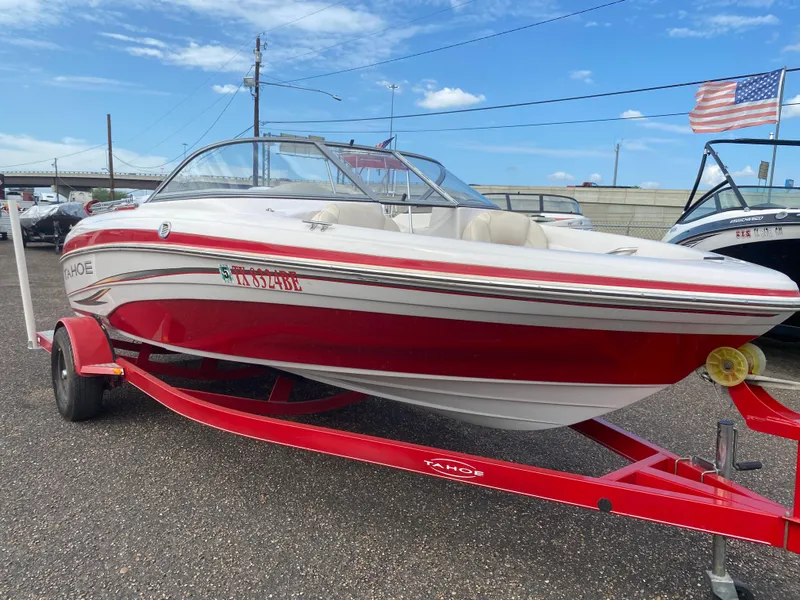 The Image of 2010 Tahoe Q5i boat on red trailer, parked outdoors with American flag in background. - 1
