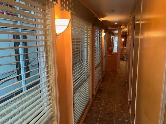 Slide: The Image of Interior hallway of a 2007 Thoroughbred houseboat with wooden paneling and large windows. - 12