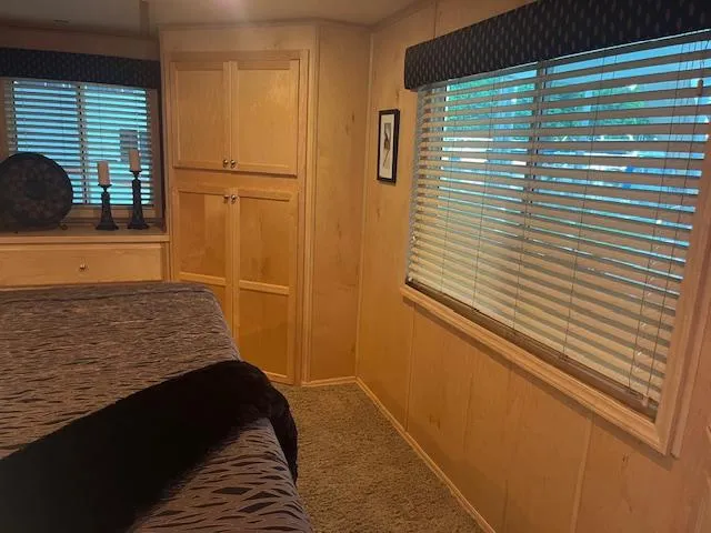Slide: The Image of Interior of a 2007 Thoroughbred houseboat bedroom with wooden paneling and large windows. - 19