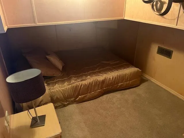 Slide: The Image of Cozy bedroom in a 2007 Thoroughbred houseboat with a bed, lamp, and wooden cabinetry. - 21