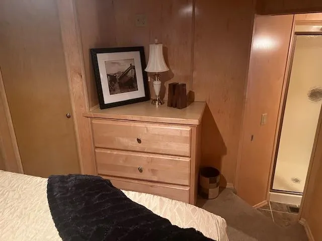Slide: The Image of Cozy bedroom in a 2007 Thoroughbred houseboat with wooden furniture and a small lamp. - 26