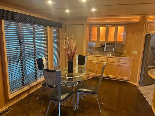 Slide: The Image of Modern kitchen and dining area in a 2007 Thoroughbred houseboat with wooden cabinetry and glass table. - 5