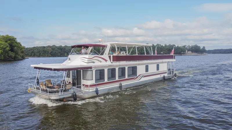 Slide: The Image of 2002 Sumerset 75 houseboat cruising on a scenic lake under a clear sky. - 0
