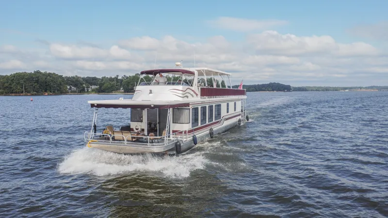 Slide: The Image of 2002 Sumerset 75 houseboat cruising on a lake under a clear sky. - 1
