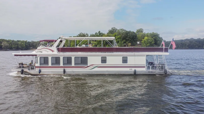 Slide: The Image of 2002 Sumerset 75 houseboat cruising on a lake with trees in the background. - 2
