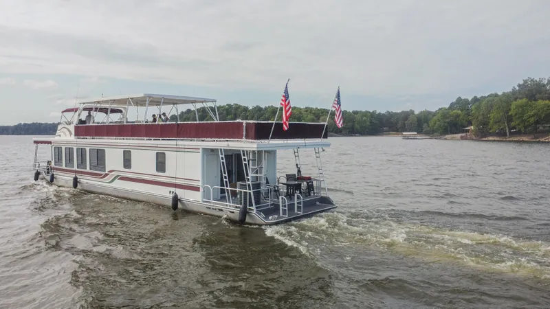 Slide: The Image of 2002 Sumerset 75 houseboat cruising on a lake with American flags. - 3