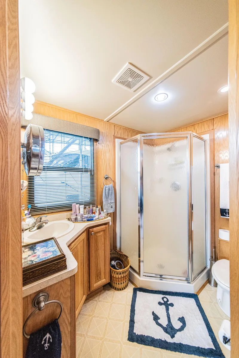Slide: The Image of 2002 Sumerset 75 bathroom with shower, wooden cabinets, nautical decor, and anchor-themed rug. - 37