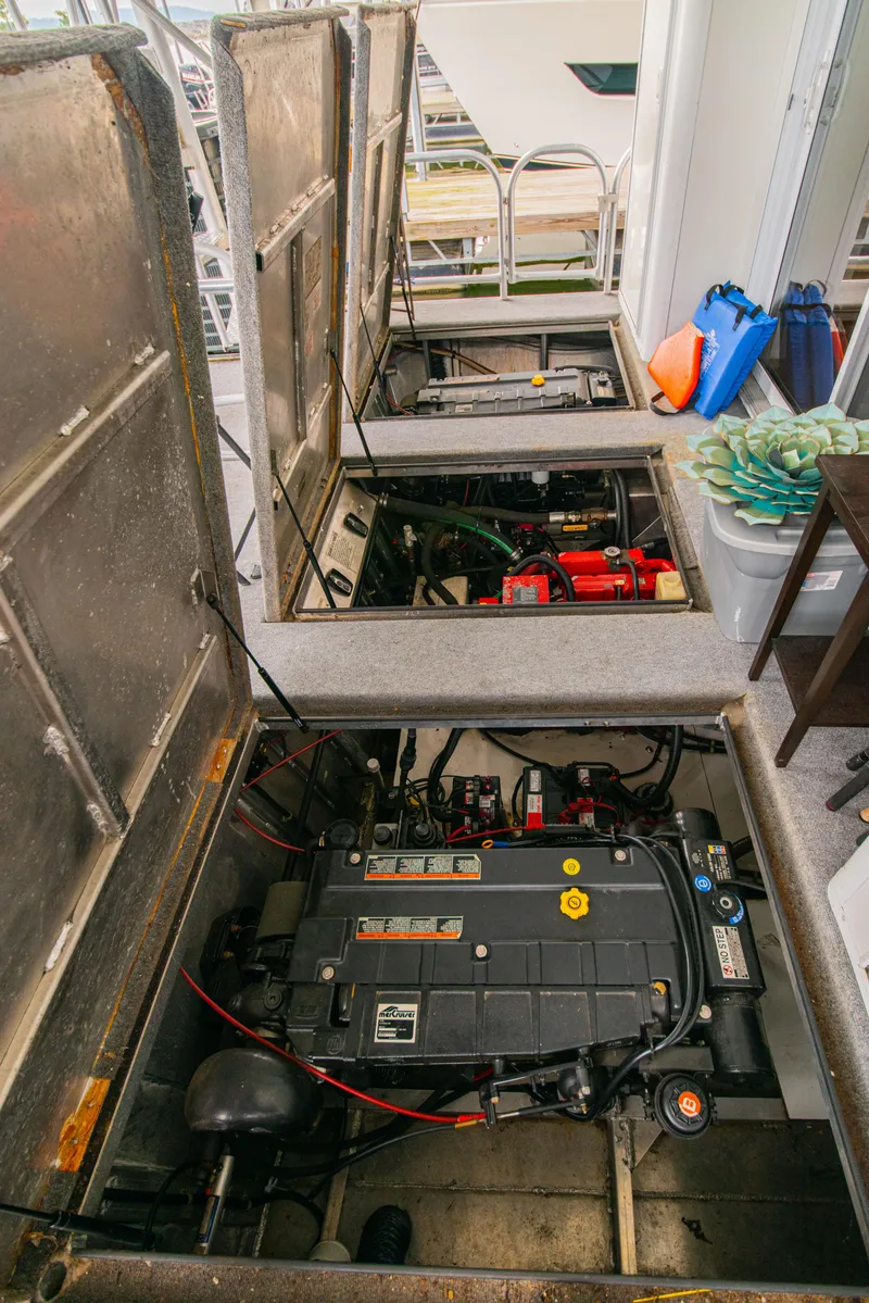 Slide: The Image of Engine compartment of a 2002 Sumerset 75 houseboat, showing mechanical components and storage. - 46