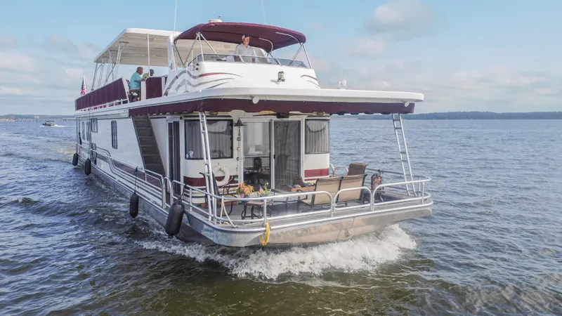 Slide: The Image of 2002 Sumerset 75 houseboat cruising on a lake under a clear sky. - 6