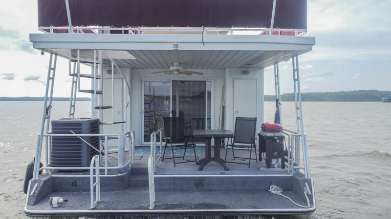 Slide: The Image of 2002 Sumerset 75 houseboat on water, featuring outdoor seating and grill. - 8