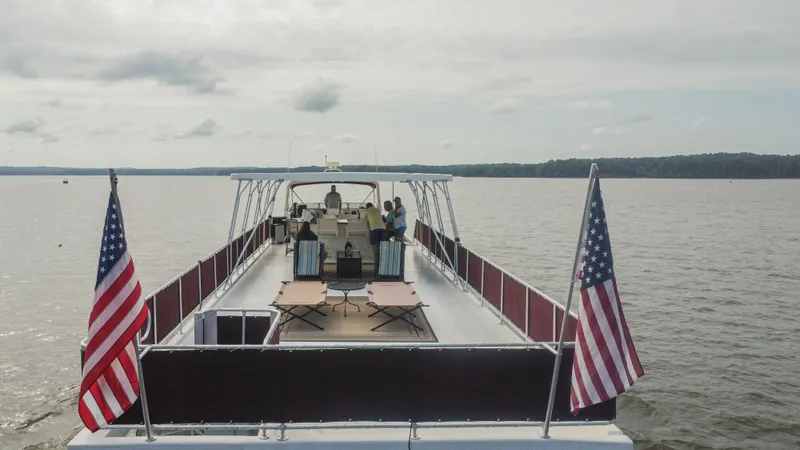 Slide: The Image of Sumerset 75 houseboat on a lake, 2002 model, with American flags and people on deck. - 9