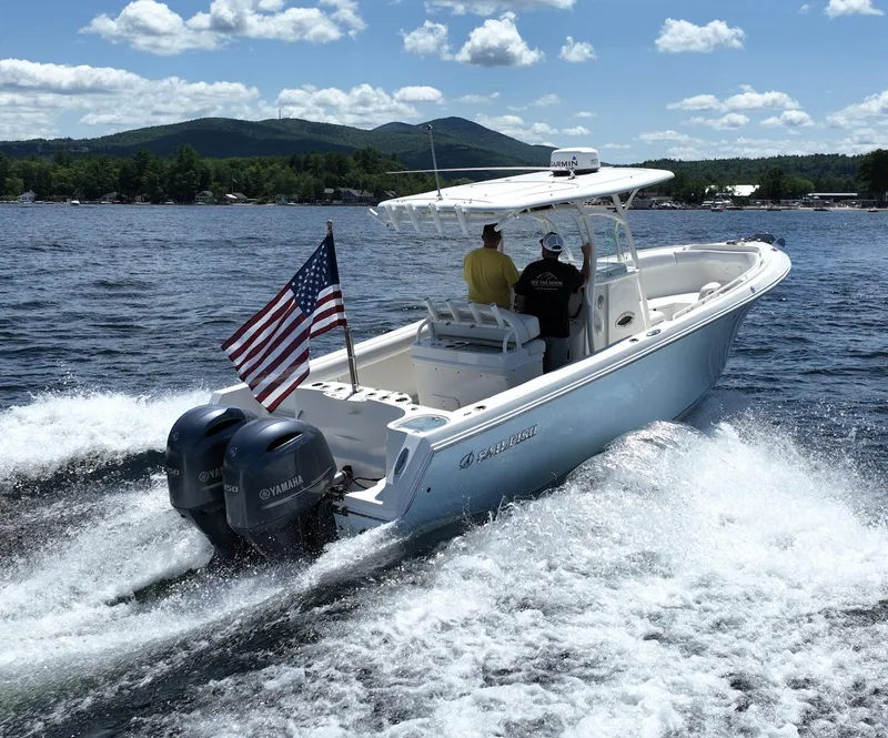 Slide: The Image of 2016 Sailfish 270 CC boat cruising on a lake with American flag and twin Yamaha engines. - 20