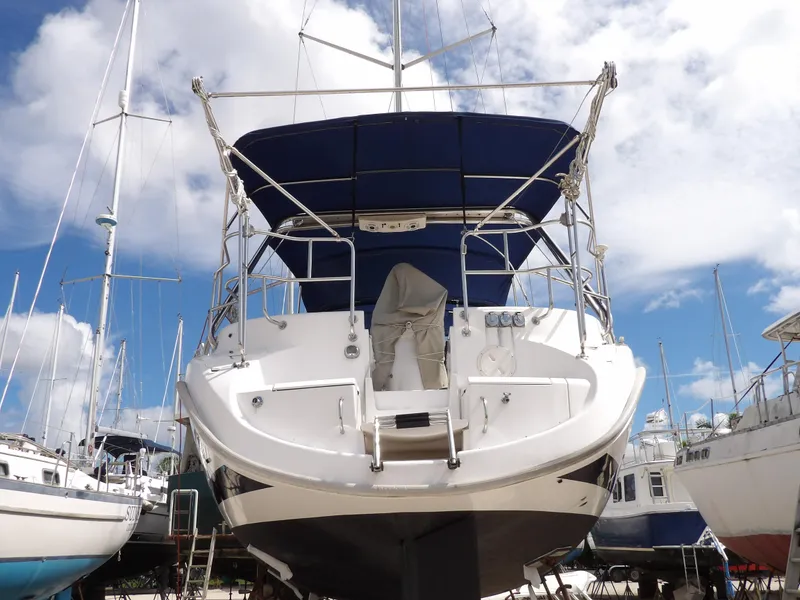 Slide: The Image of Hunter 460 sailboat, 2000 model, docked with blue canopy against a cloudy sky. - 4
